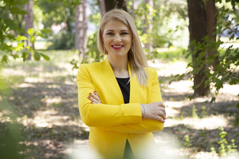 Dr. Zorana Pravdić im gelben Blazer mit verschränkten Armen in einem sonnigen Park
